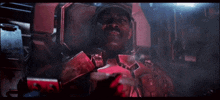 a man in a red armored suit is sitting in a dark room
