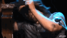 a man singing into a microphone with a gifs.com watermark