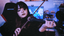 a woman is playing a violin in front of a chair that says akracing on it