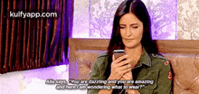 a woman is sitting on a couch looking at her cell phone and says alla says you are dazzling and you are amazing