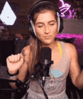 a woman wearing headphones is sitting in front of a microphone and making a funny face .