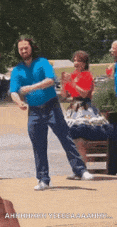 a man in a blue shirt is dancing in front of a woman sitting on a chair .