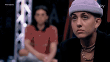 a woman wearing a purple beanie and a necklace is sitting in front of a man .