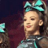 a cheerleader with a blue bow in her hair is smiling and looking at the camera .