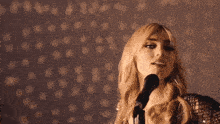 a woman with blonde hair is singing into a microphone with her arms outstretched