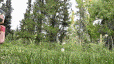 a person standing in a grassy field with trees in the background and a bottle that says ' coca cola ' on it