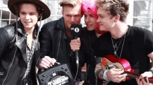 a group of young men are posing for a picture and one of them is holding a microphone that says bbc radio 1 on it
