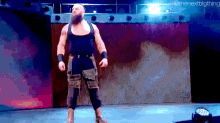 a bearded wrestler is standing on a stage in front of a large screen .