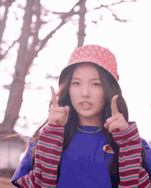 a girl wearing a hat and a striped shirt is giving a thumbs up sign