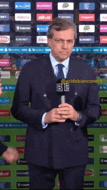 a man in a suit and tie is holding a microphone with the letters da on the front