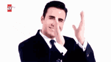 a woman is smiling and making a peace sign with her hands in front of her face .