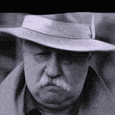 a man with a mustache wearing a hat and a trench coat