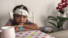 a little girl with a bandage on her head sits at a table with a youtube logo in the background