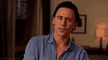 a man in a blue shirt is making a funny face and looking at the camera .