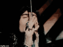 a person is singing into a microphone with a ring on their finger .