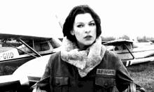 a black and white photo of a woman wearing a army jacket