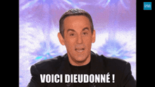 a man in a black suit says voici dieudonné