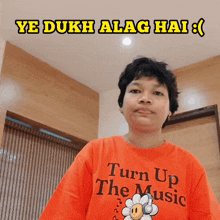 a person wearing an orange t-shirt that says turn up the music