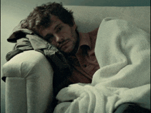 a man wrapped in a white blanket is sitting on a white couch