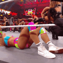 a woman is laying on the ground in a wrestling ring with the word nxt on the screen behind her