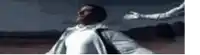 a man in a white jacket is standing in a dark field with his arms outstretched