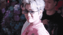 a close up of a person wearing glasses and a pink shirt that says ' mcm ' on it