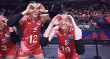 female volleyball players wearing red uniforms with the numbers 12 and 19 on them