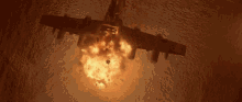 a plane is flying through the air with a huge explosion behind it .