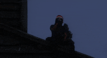 a man wearing a santa hat sitting on a ledge