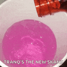a bottle of purple liquid is being poured into a cup filled with ice .