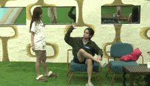 a man is sitting in a chair with his leg up and a woman is standing behind him