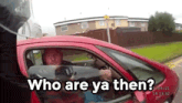 a man driving a red car with the words who are ya then below him