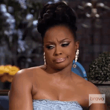 a woman in a blue dress is sitting on a couch with a bravo logo on her chest