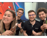 a group of people are posing for a picture while holding bottles of beer ..