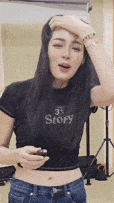 a woman wearing a black crop top that says story