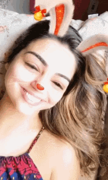 a woman wearing bunny ears and a fake nose smiles for the camera