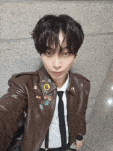 a young man wearing a brown leather jacket and a black tie