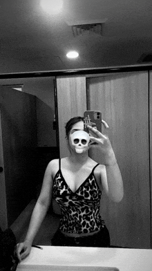 a woman is taking a selfie with a skull mask on her face