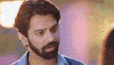 a man with a beard and long hair is looking at another man .