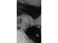 a black and white photo of a girl with long hair laying on a bed .