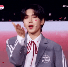 a young man wearing a boys planet jacket and tie