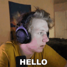 a man wearing headphones and a yellow shirt is saying hello