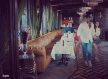 a man and a woman are walking through a restaurant with the name sophie on the bottom right