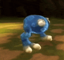 a blue stuffed animal with white feet and legs is walking on a field .