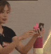 a woman is taking a selfie with her phone while holding a pink water bottle .