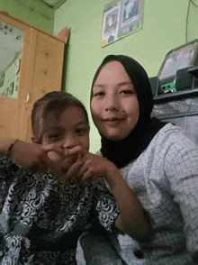 a woman in a hijab holds a little girl in her lap