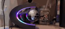 a bottle of m & m 's sits on a desk next to a globe