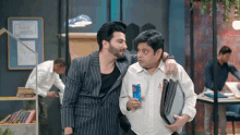 two men are standing next to each other and one is holding a can of red bull