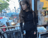 a woman in a black jacket is standing in front of a store with a sign on the wall that says ' a '