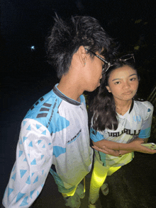 a boy and a girl are standing next to each other and the boy is wearing a shirt that says ' lithium '